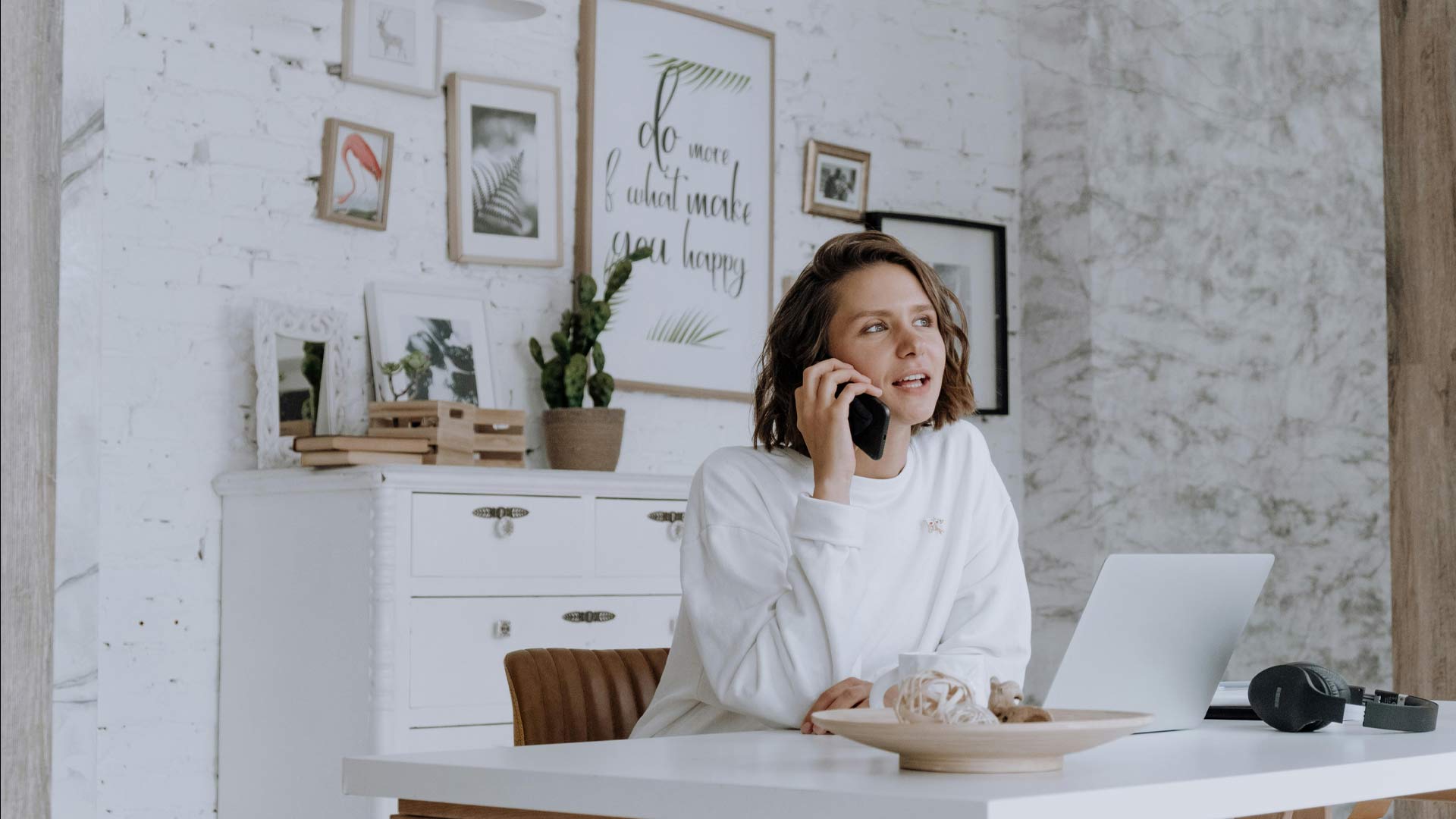 Eine Frau sitzt bei einem Schreibtisch und telefoniert
