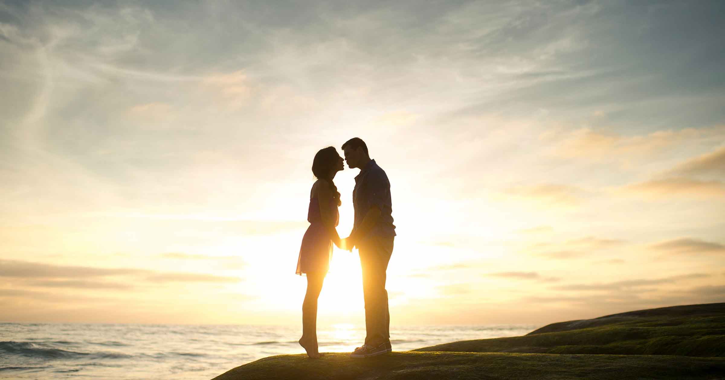 Ein Pärchen steht im Sonnenaufgang am Meer