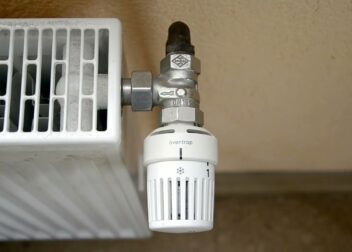 Hand dreht am Thermostat eines Heizkörpers