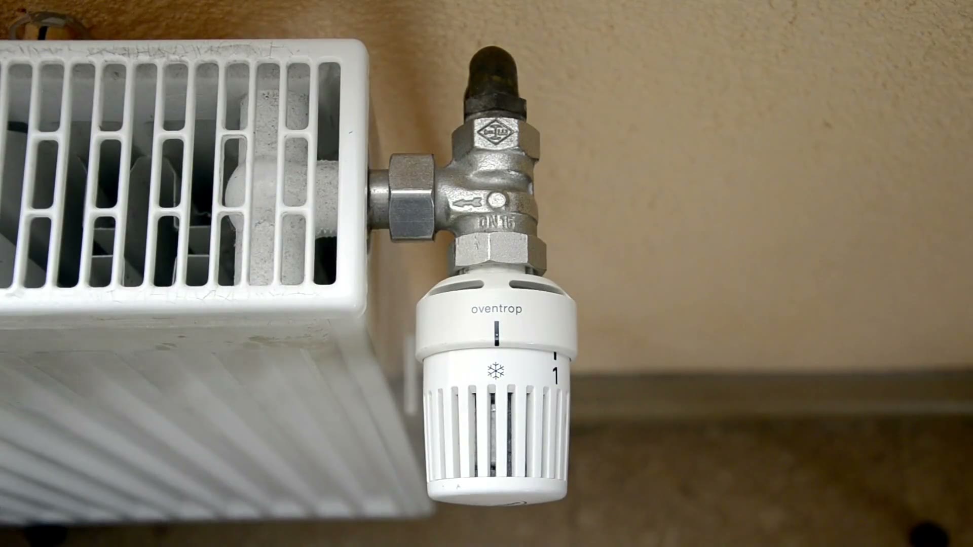 Hand dreht am Thermostat eines Heizkörpers