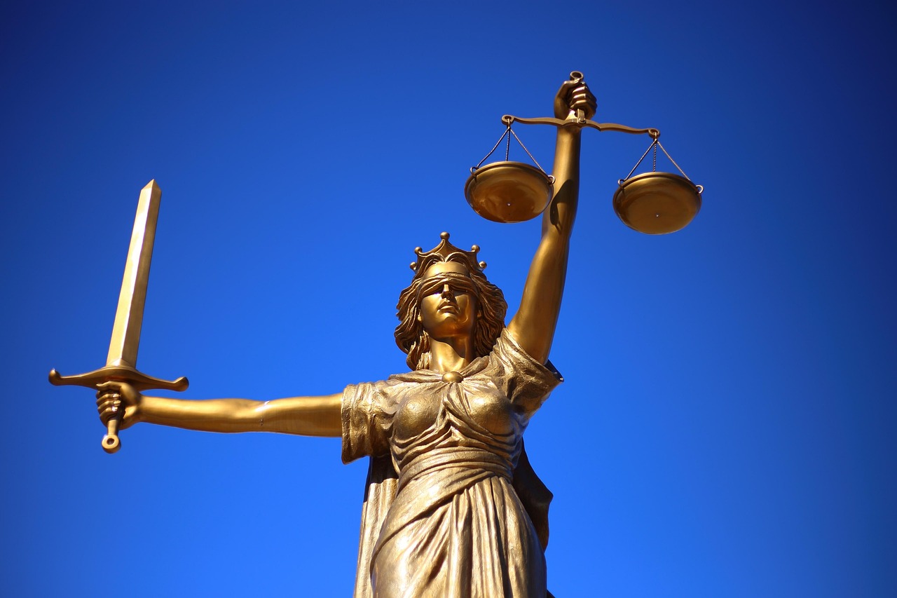 Statue der Justitia mit Waage und Schwert vor blauem Himmel